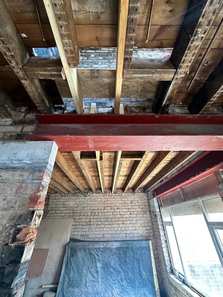 Red steel RSJs installed under exposed floor joists